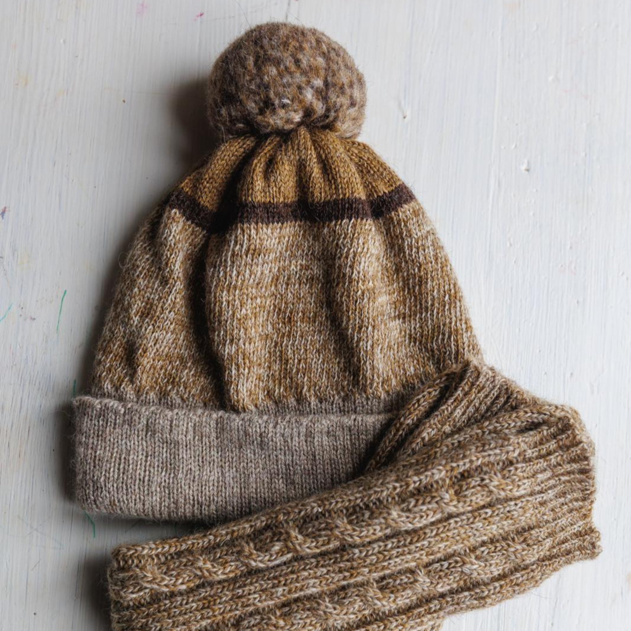 Knitted hat and socks set on a light wooden surface